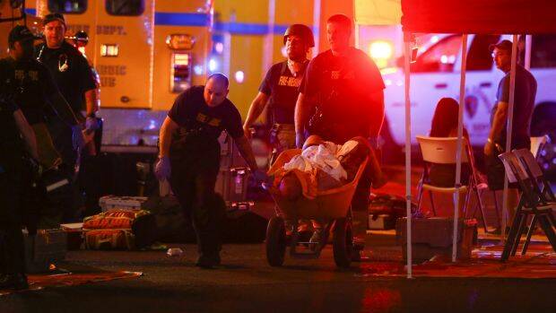 A wounded person is walked in on a wheelbarrow as Las Vegas police respond during the shooting. Photo: AP