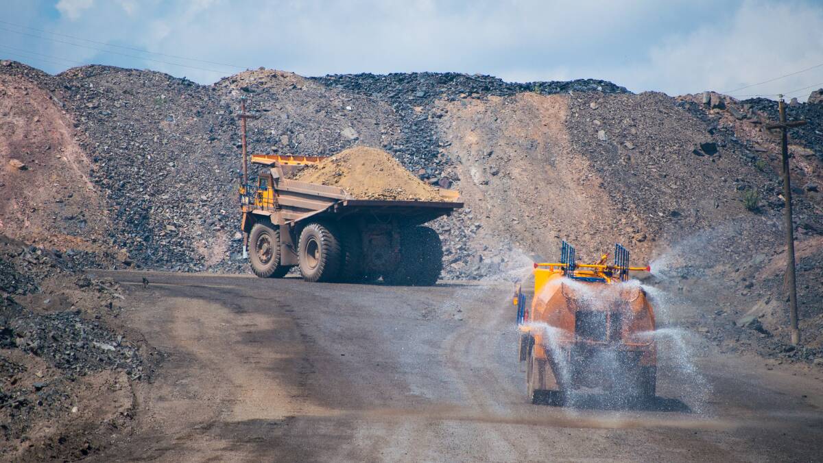 Heavy truck pours the road with water in the iron ore quarry. Photo: SHUTTERSTOCK.