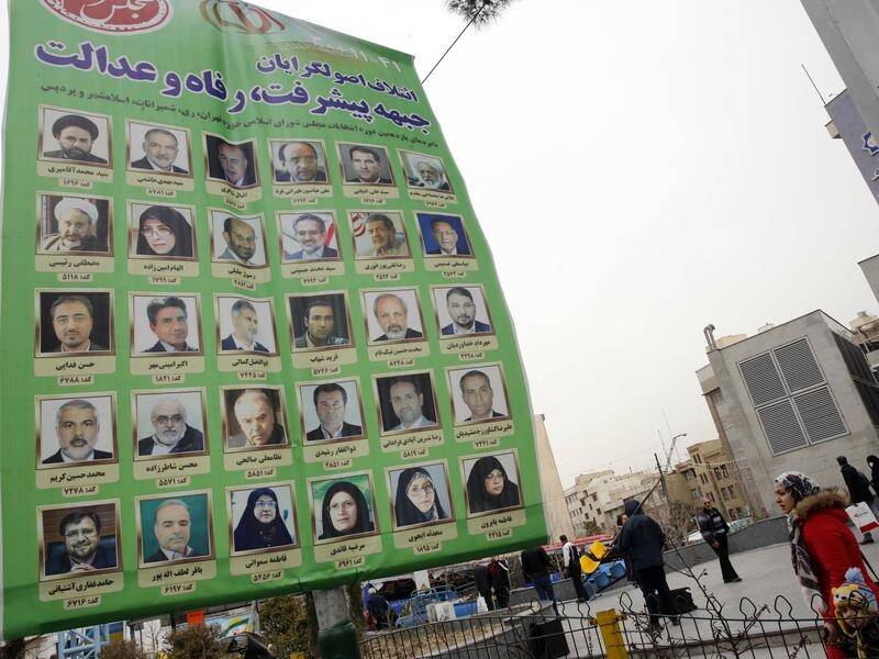 Iranians walk past an electoral billboard in a street in Tehran.