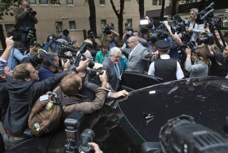 Entertainer Rolf Harris (C) is surrounded by the media as he leaves Southwark Crown Court in London June 30, 2014. Harris, a mainstay of family entertainment in Britain and Australia for more than 50 years, was found guilty on Monday of 12 charges of indecently assaulting young girls over a period of nearly 20 years.  REUTERS/Neil Hall (BRITAIN - Tags: ENTERTAINMENT CRIME LAW)