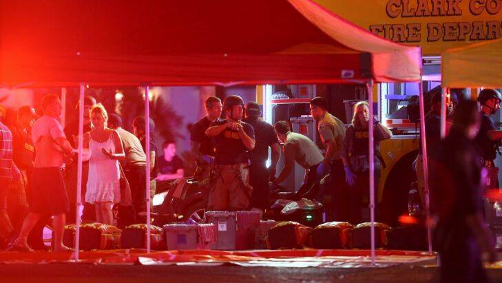 Medics treat the wounded as Las Vegas police respond during an active shooter situation on the Las Vegas Stirp in Las Vegas Sunday, Oct. 1, 2017. Multiple victims were being transported to hospitals after a shooting late Sunday at a music festival on the Las Vegas Strip. (Chase Stevens/Las Vegas Review-Journal via AP)