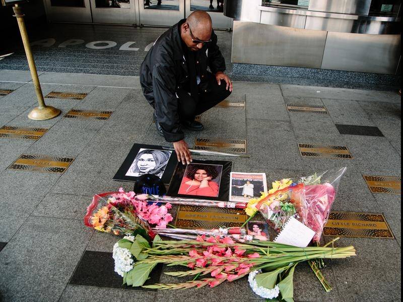 A man pays respects as flowers and photographs are seen in tribute to Aretha Franklin in New York.