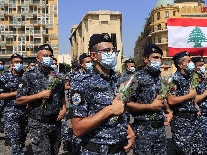 Police hold flowers to mark the first anniversary of Beirut's massive port blast.